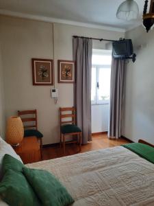 um quarto com uma cama, 2 cadeiras e uma janela em Casa Araci em Vieira do Minho