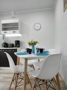 uma mesa de jantar branca com cadeiras brancas em Hiiumaa Family Apartments em Kärdla