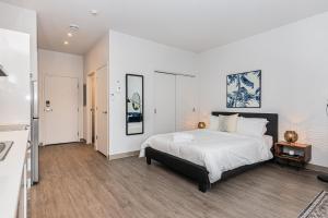 a bedroom with a large bed with white sheets at Modern and New Studio in the Heart of the City by Den Stays in Montréal
