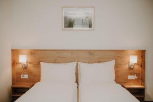 a bed with two white pillows and two lamps at Kirchenwirt Mayr in Franking