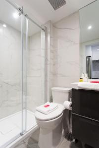 a white bathroom with a toilet and a shower at The Santamaria Golden Palms Studio by Den Stays in Montréal