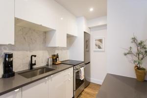 Scandinavian Studio with Full Kitchen and Bath by Den Stays في مونتريال: مطبخ أبيض مع حوض وأعلى كاونتر