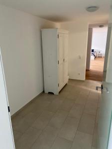 an empty room with a white cabinet and a tile floor at Großzügiges Apartment in Biberach an der Riss in Biberach an der Riß +6 photos