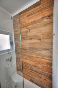 La salle de bains est pourvue d'une douche et d'un mur en bois. dans l'établissement Apartamentos Belo Horizonte, à Portimão