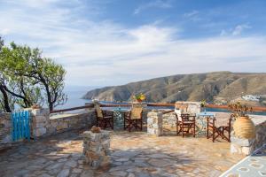 eine Terrasse mit einem Tisch, Stühlen und Meerblick in der Unterkunft Uranos Studios in Amorgós