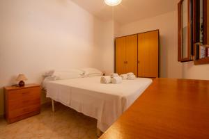 1 dormitorio con 1 cama con sábanas blancas y armario de madera en Appartamenti Saccomanni, en Marina di Leuca