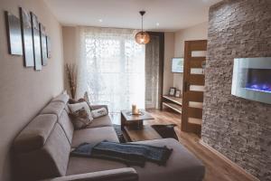 uma sala de estar com um sofá e uma parede de pedra em Apartmán Zara em Telgárt