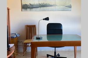 a glass desk with a chair and a lamp at Apartamento Turistico San Cristobal in Plasencia