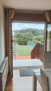 a sliding glass door to a balcony with a view of a yard at Casa JyM Fontela 24 in O Pedrouzo