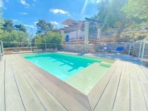 a large swimming pool with a wooden deck and a house at Villa Aurora in Corsano