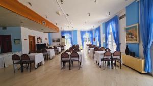 einen Bankettsaal mit weißen Tischen und Stühlen sowie blauen Vorhängen in der Unterkunft Artemis in Prinos