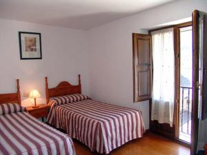 a bedroom with two beds and a window with a door at Apartamento Miguel Torla Ordesa in Torla