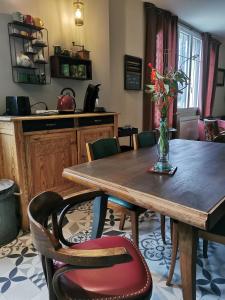 a dining room table with a vase of flowers on it at L'en vert appartement in Bagnères-de-Bigorre