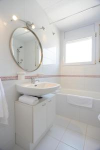 a white bathroom with a sink and a mirror at Sant Mori in Empuriabrava