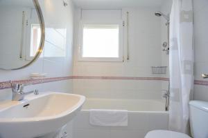 a white bathroom with a sink and a tub at Sant Mori in Empuriabrava
