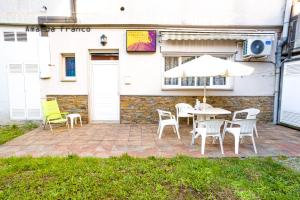 une terrasse avec une table, des chaises et un parasol dans l'établissement Albergue de Peregrinos Ultreia et Suseia, à Sigüeiro