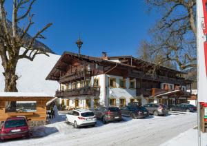 ein großes Gebäude mit Autos im Schnee in der Unterkunft Gasthof Oberstegen in Söll