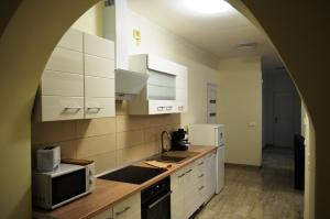 a kitchen with white cabinets and a microwave at Henrietta - Violetta Apartman in Hajdúszoboszló