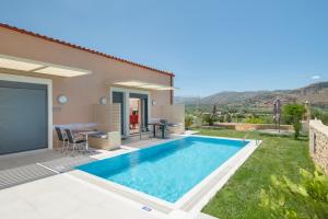 uma villa com uma piscina, uma mesa e cadeiras em Marinas Villas em Amoudara Herakliou