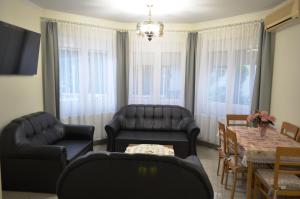 a living room with black leather furniture and a table at Henrietta - Violetta Apartman in Hajdúszoboszló