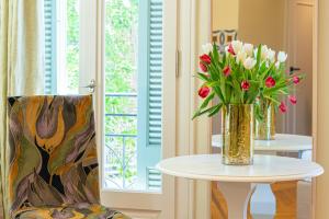 a vase of flowers on a table next to a chair at IPELHOME - Plaka Boutique Apartments in Athens