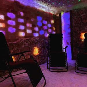 een kamer met stoelen en een bakstenen muur met paarse verlichting bij Willa Karkonoska in Karpacz