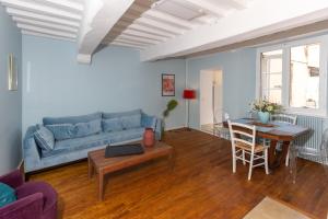 a living room with a blue couch and a table at LES URSULINES Centre Historique de BAYEUX in Bayeux