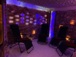Pokój z 3 krzesłami i kamienną ścianą z niebieskimi światłami w obiekcie Willa Karkonoska w mieście Karpacz