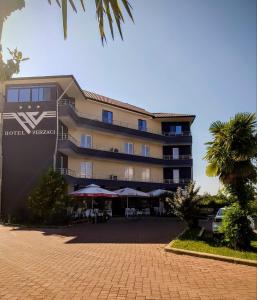 ein großes Gebäude mit Tischen und Sonnenschirmen davor in der Unterkunft Hotel Verzaci in Rinas