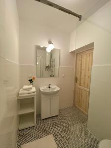 Baño blanco con lavabo y espejo en Miły Apartament en Ustrzyki Dolne