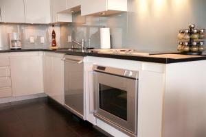 cocina con armarios blancos, fregadero y horno en Your Alternative to a Five Star Hotel - Premium Location, en Vancouver