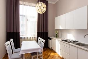 cocina con armarios blancos, mesa y sillas en Апартаменти в центрі міста, en Ivano-Frankivsk