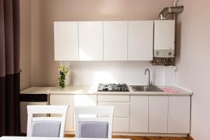 a kitchen with white cabinets and a sink and chairs at Апартаменти в центрі міста in Ivano-Frankivsʼk