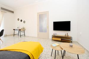 Habitación blanca con cama y TV de pantalla plana. en Alion House en Rodas