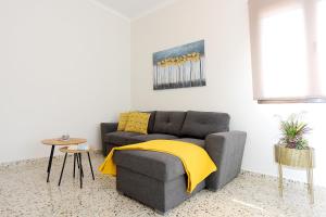 een woonkamer met een grijze bank en een gele deken bij Alion House in Rhodos-stad