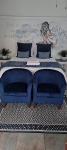 een slaapkamer met een blauw bed en 2 blauwe stoelen bij Forget me not Selfcatering Apartments in Nelspruit