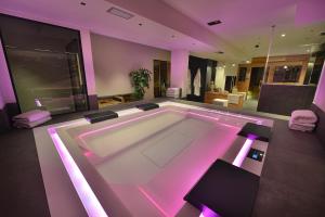 una grande vasca da bagno con illuminazione rosa in una stanza di Hotel Astoria a Livigno