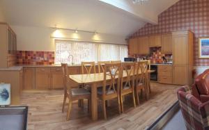 a kitchen with a wooden table and wooden chairs at Loch Rannoch Highland Lodge 44 in Kinloch Rannoch