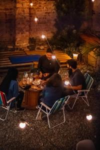Social Hostel Café e Bar في كوريتيبا: مجموعة من الناس يجلسون حول طاولة في الفناء