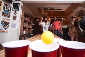 a man throwing a ping pong ball over a table at Social Hostel Café e Bar in Curitiba