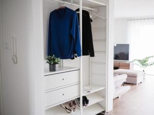 a white closet with a blue shirt and a blue shirt at Moderne Ferienwohnung mit Seeblick & Terrasse 96qm in Großräschen