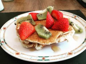 a plate of pancakes with strawberries and kiwis on it at Cae Garw B&B in Betws-y-coed