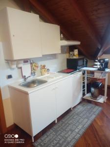 una cocina con armarios blancos y fregadero en Villa Dina, en Olgiate Olona