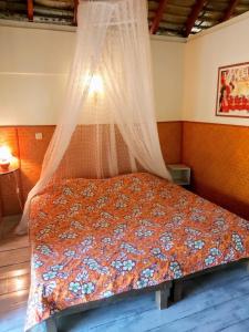 a bed with a canopy in a bedroom at HUAHINE - Bungalow Opuhi in Fare