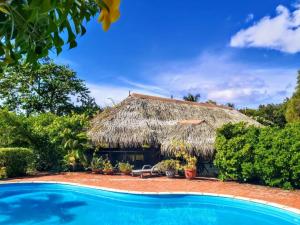 a house with a thatched roof and a swimming pool at HUAHINE - Bungalow Opuhi in Fare