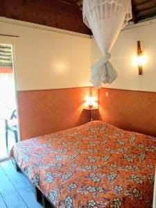 ein Schlafzimmer mit einem Bett mit Vorhang darauf in der Unterkunft HUAHINE - Bungalow Vanille 2p in Fare
