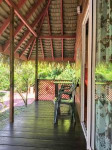 un porche con un banco y una mesa en HUAHINE - Bungalow Tiare en Fare