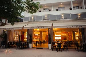a restaurant with tables and chairs in front of a building at Hotel Vila Mare in Durrës
