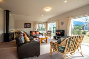 a living room with a couch and chairs and a tv at 22 Tarndale Place in Hanmer Springs