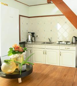 una cocina con armarios blancos y una mesa con flores en B&B De Horizon, en Urk